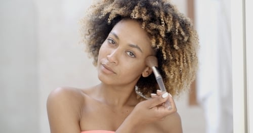 Woman Applying Makeup with Brush in Bathroom