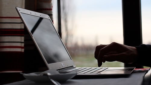 Mann arbeitet am Laptop und trinkt Kaffee