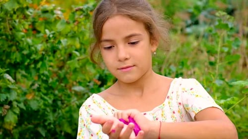 The Child Plays with a Slime in Her Hands