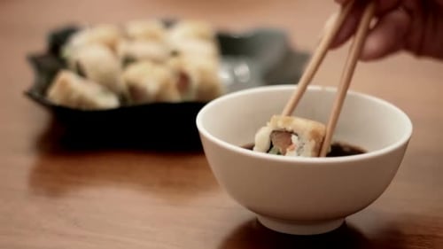 Dipping Sushi Roll in Soy Sauce Close Up