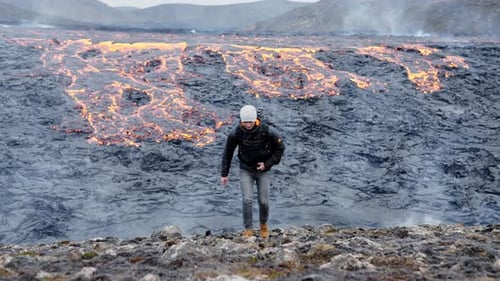Man Walking on Rocky Terrain Near Lava