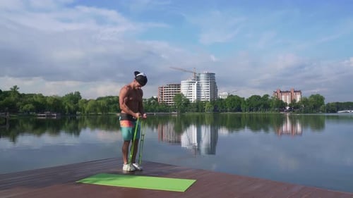 Man Exercising Biceps with Resistance Bands on Pier