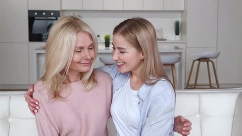 Affectionate Mother and Daughter Hugging on White Sofa