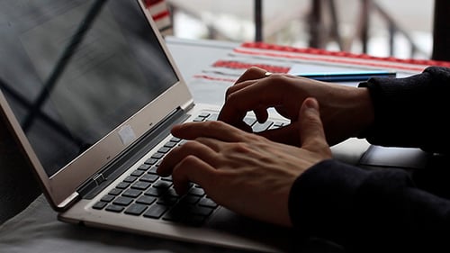 Hands Typing on Laptop and Taking Notes