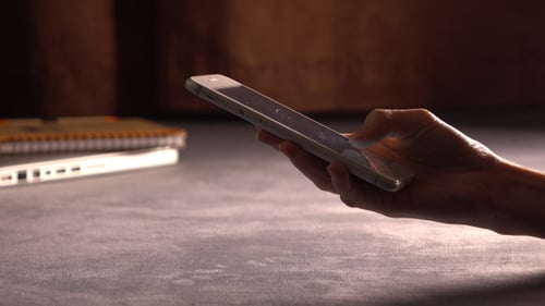Hand Uses Cellphone at Desk