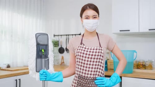 Young Woman with Mop Wearing Face Mask in Kitchen