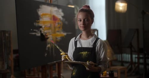 Young Woman Artist Holding Paintbrush in Studio