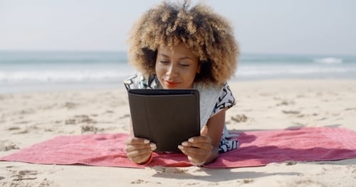 Woman Uses A Tablet On The Beach