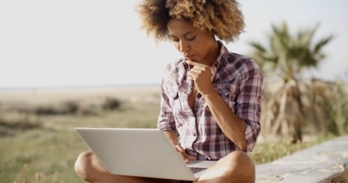 Woman Uses Laptop Outdoors on Beach