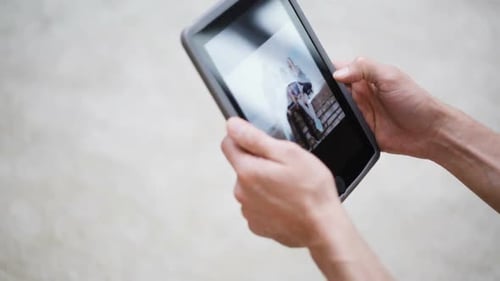 Paar Hände mit Tablet-PC beim Betrachten von Fotos zu Hause 2