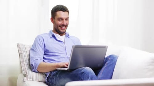 Young Adult Man Laughing While Using Laptop