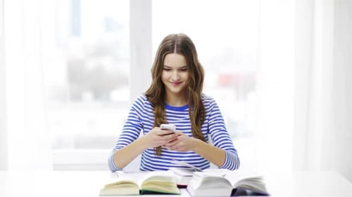 Young Woman Texting with Books on Table