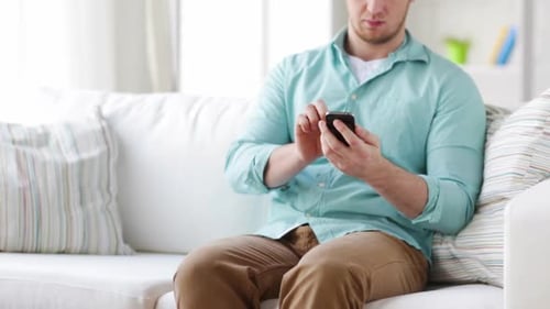 Man Uses Smartphone While Sitting on Couch