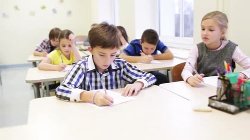 Group Of School Kids Writing Test In Classroom 2