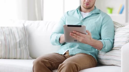 Young Adult Using Tablet on Couch Indoors
