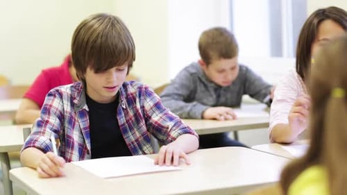 Group Of School Kids Writing Test In Classroom 5