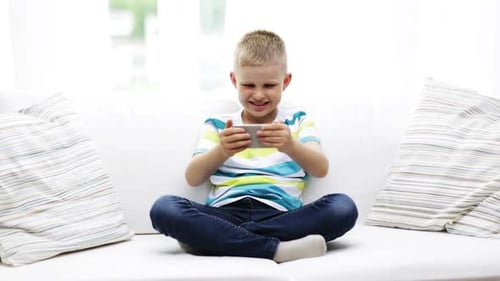 Boy Playing Excitedly on Mobile Phone on Couch