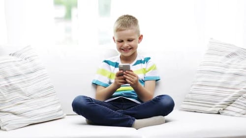 Boy Smiling and Playing with Phone on Couch
