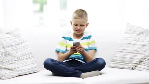 Smiling Boy Using Phone on Couch at Home