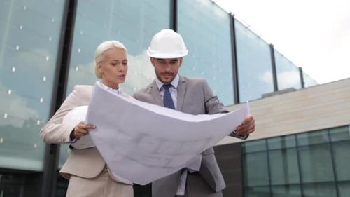 Architects Reviewing Blueprints Outside Modern Building