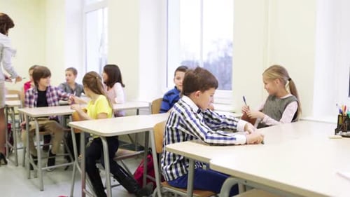 Teacher Giving Pens To School Kids In Classroom 2
