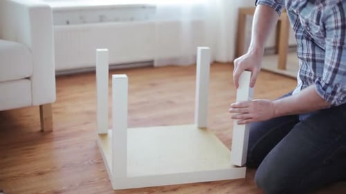 Close Up Of Male Hands Assembling Legs To Table