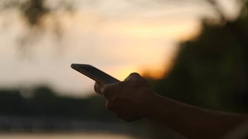 Hand Holding Phone at Sunset