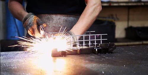 Welder Assembling Metal Cage with Welding Torch
