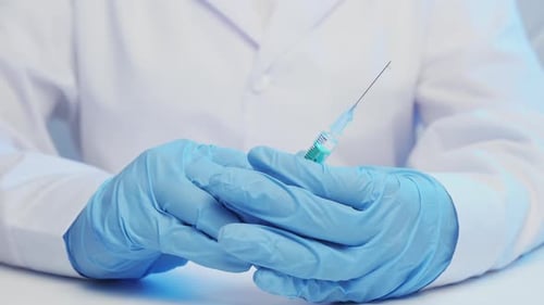 Close-up of Gloved Hands Holding Syringe