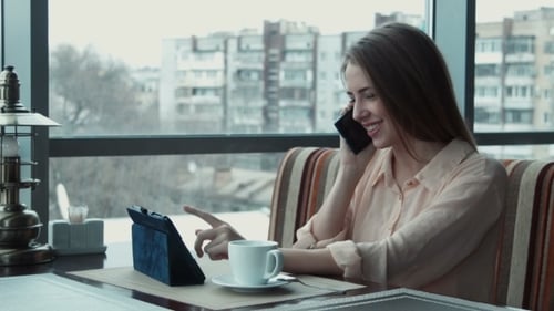 Woman Talking On Phone, Using Tablet in Cafe