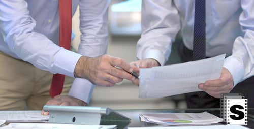 Men Reviewing Business Charts in Modern Office Setting