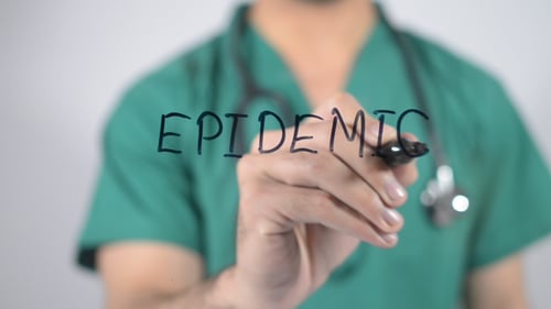 Healthcare Worker Writing Epidemic on Clear Surface