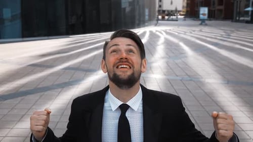 Celebrating Man in Suit Raises Arms in Triumph