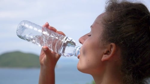 Woman Drinking Water Bottle on Tropical Island