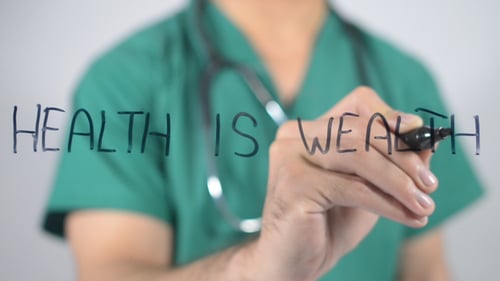 Doctor Writing Health is Wealth on Glass