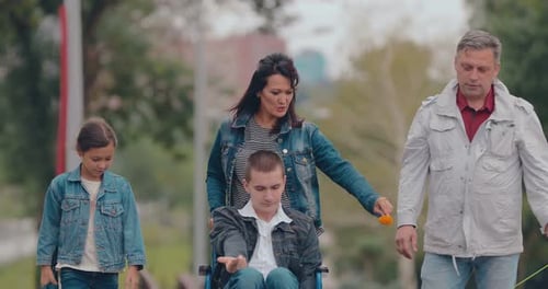 Guy in a Wheelchair for a Walk with His Family. Help People with Disabilities. Portrait View