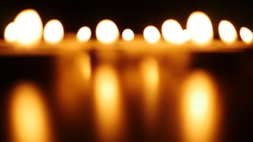 Blurred Candle Flames Reflect in the Darkness