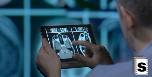 Adult Reviews Medical Scan on Tablet in Hospital