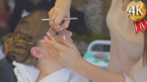 Stylist legt einen Lidschatten auf und schminkt sich