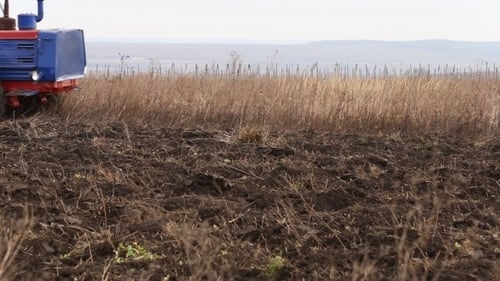 Tractor Tills Harvested Field in Rural Environment