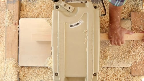 Woodworker Using Thickness Planer in Workshop