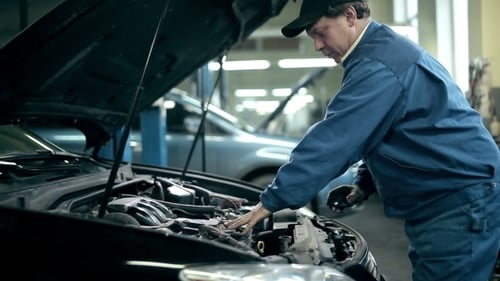 Mechanic Examining Car Engine in Auto Shop