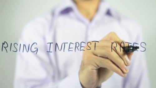 Man Writes Rising Interest Rates on Clear Surface