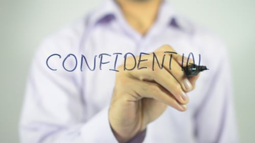Hand Writes Confidential on a Clear Surface