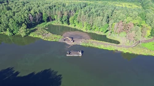 Der Bagger entlädt Sand ans Ufer
