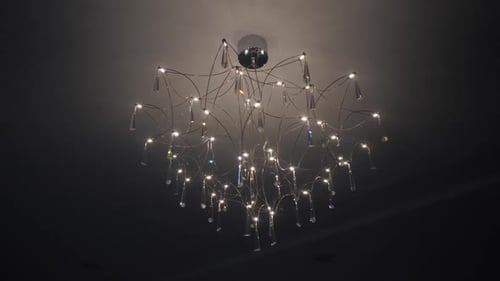 Schöner eleganter Kronleuchter mit Dioden und Kristallen an der dunklen Decke