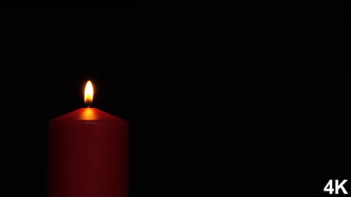 Burning Red Candle Against Black Background