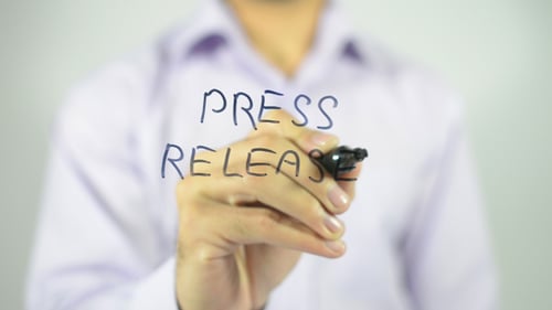 Hand Writes Press Release on Glass Surface