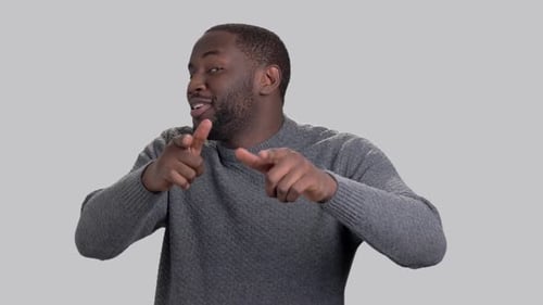 Fröhlicher afroamerikanischer Typ auf grauem Hintergrund.