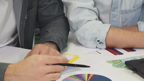 Ausgeschnittene Aufnahme von zwei Geschäftskollegen, die über die Prüfung von Dokumenten sprechen